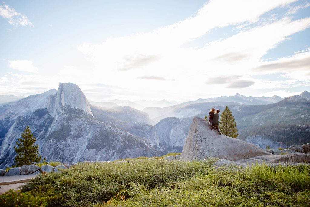 Couple hugging on a rock during a glacier point proposal 